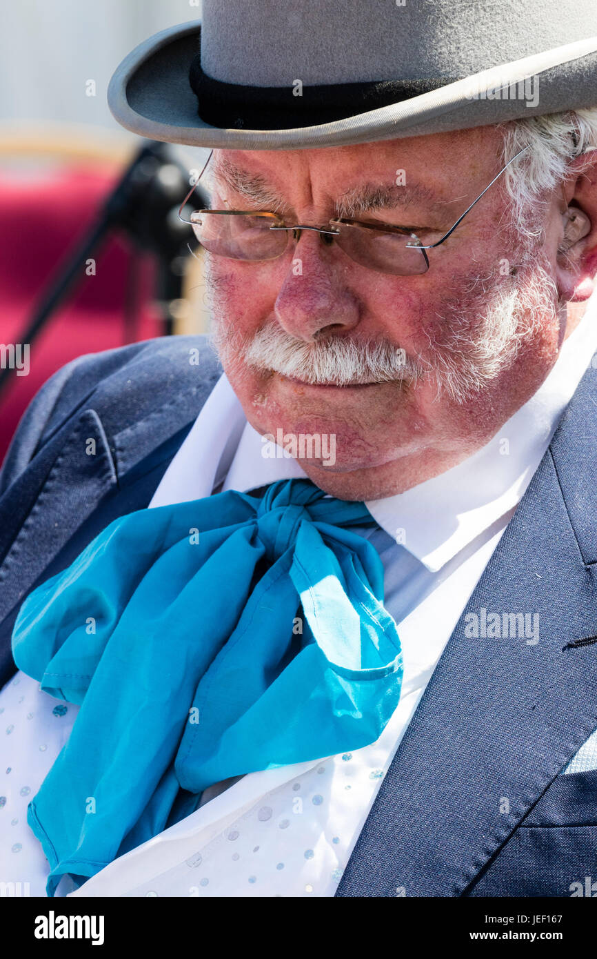 Ritratto di classe superiore senior uomo, 50s, con i baffi, lato burns e indossa gli occhiali. Vestito in costume Vittoriano, cravat blu e grigio top hat. Foto Stock