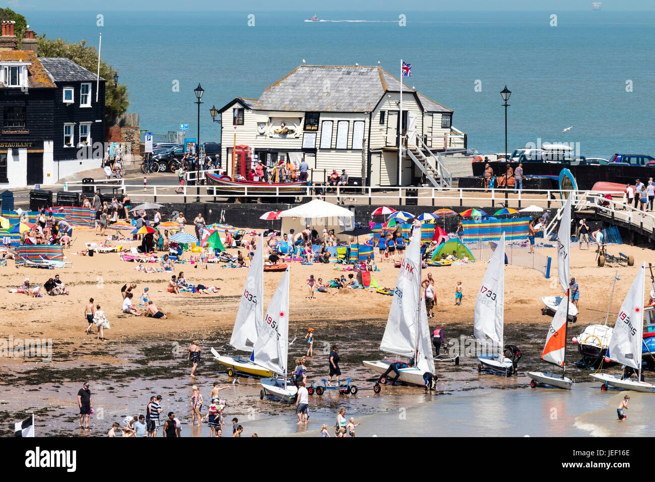 Broadstairs famosa vita ex stazione delle barche in legno edificio bianco sul molo del porto. Primo piano folle sulla spiaggia in estate il sole. Foto Stock