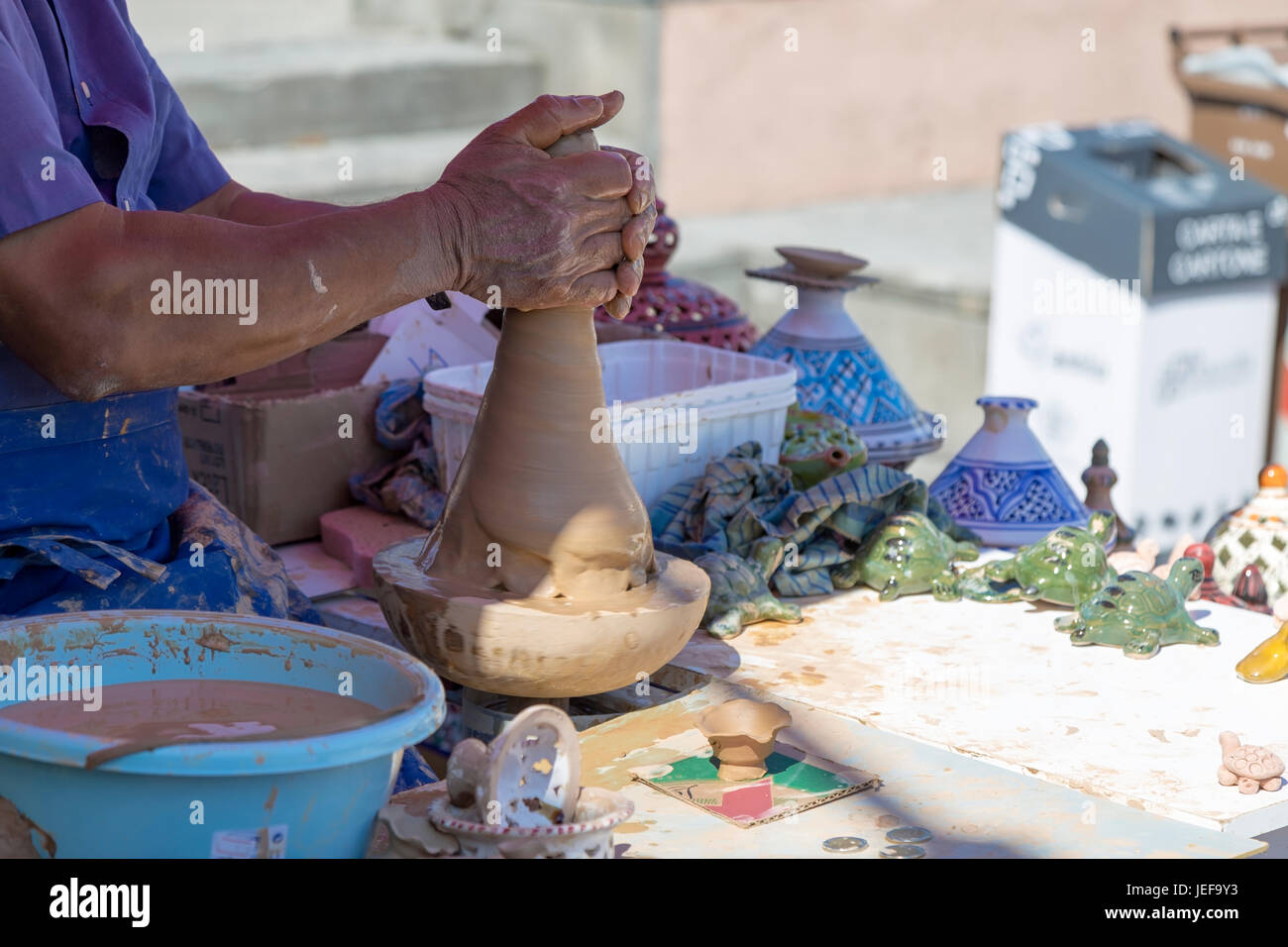 Mani di craftswoman rendendo terraglie di argilla all'aperto mentre seduto a tavola Foto Stock