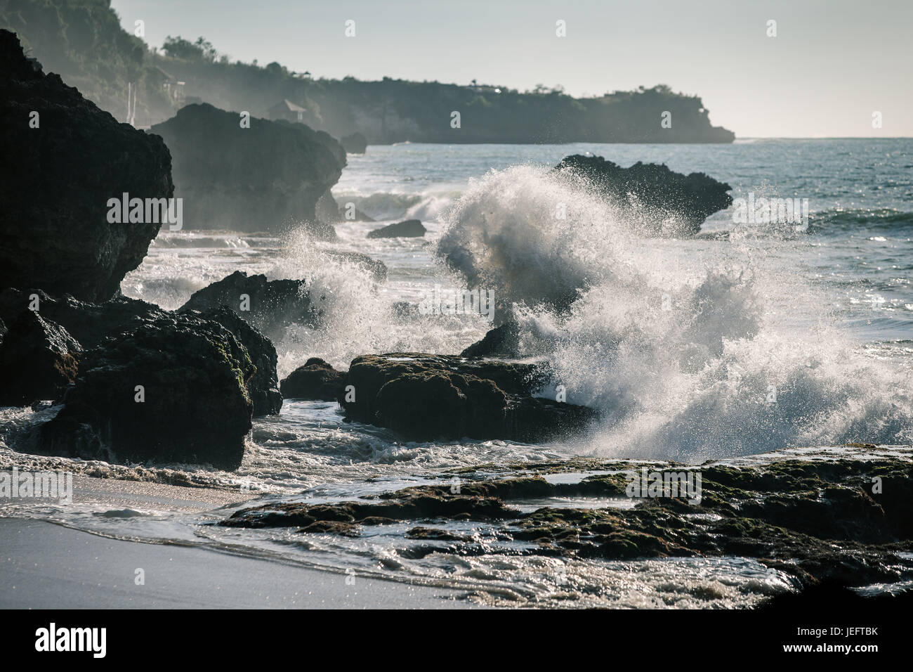 Ocean onde che si infrangono sulle rocce al tramonto Foto Stock