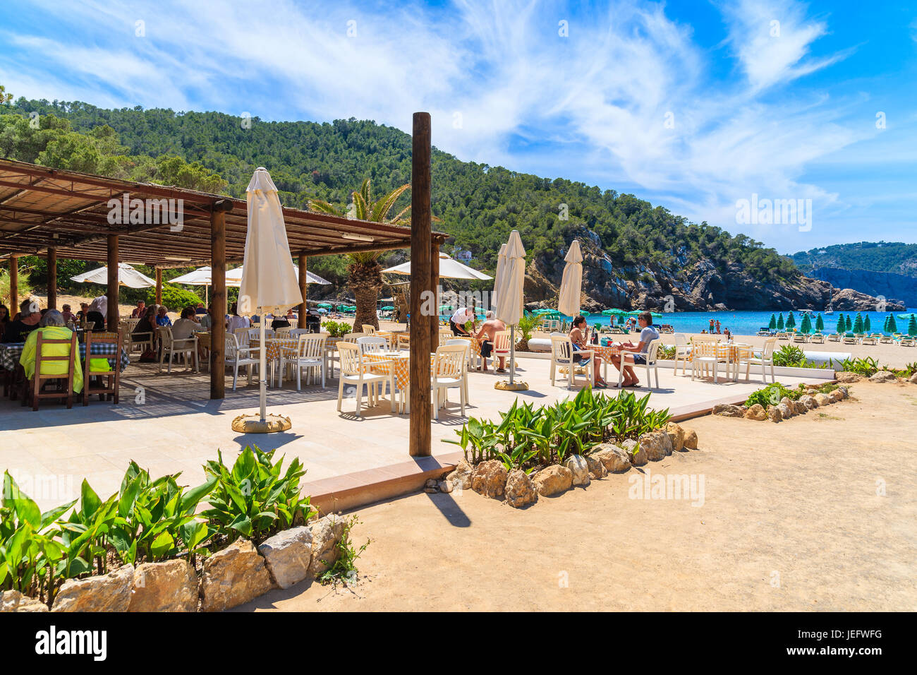 CALA Spiaggia Benirras, isola di Ibiza - Maggio 16, 2017: persone sedute a tavole di ristorante su terrazza su Cala Spiaggia Benirras, isola di Ibiza, Spagna. Foto Stock