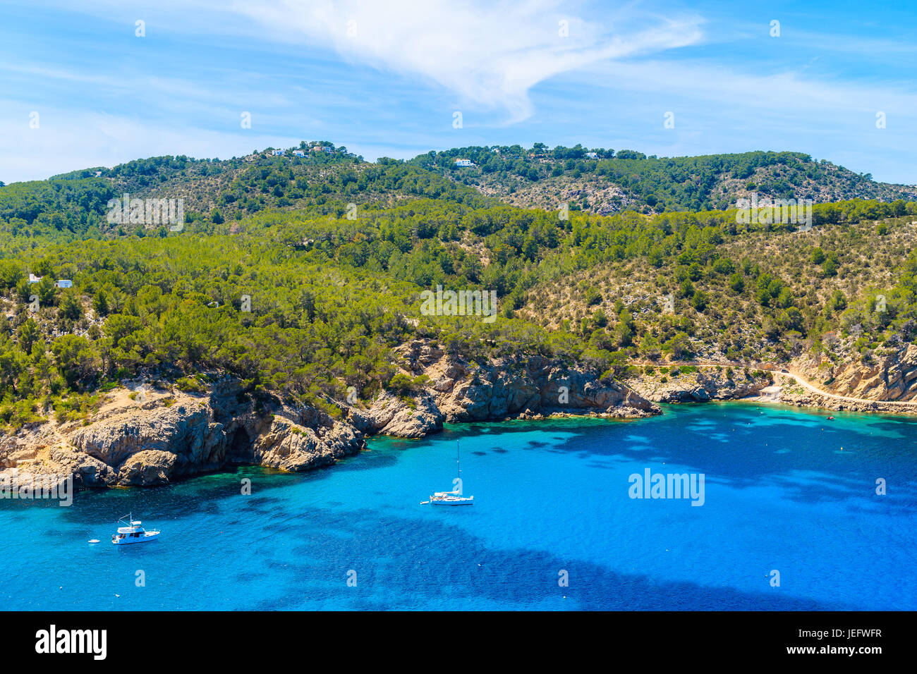 Barche a vela blu azzurro mare sulla costa settentrionale dell'isola di Ibiza tra Cala Xarraca bay e Cala Benirras bay, Spagna. Foto Stock