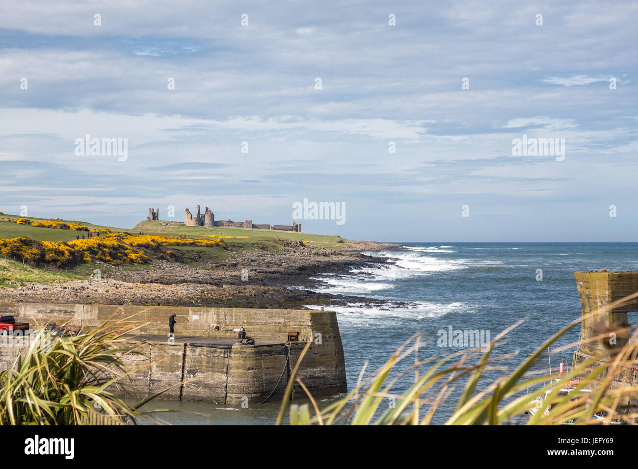 Vista del castello di Dunstanburgh dal porto di Craster, Northumberland, England, Regno Unito, Europa. Foto Stock