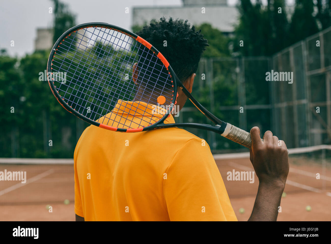 Vista posteriore ritratto di un uomo a giocare nel campo da tennis all'aperto Foto Stock