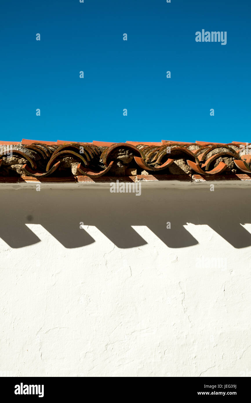 Le tegole di sfumature sporgente su una facciata dipinta di bianco Foto Stock