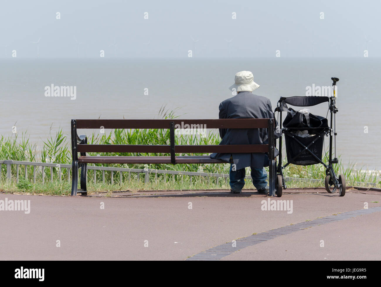 Un uomo anziano seduto su una panchina nel pensiero profondo UK. Foto Stock