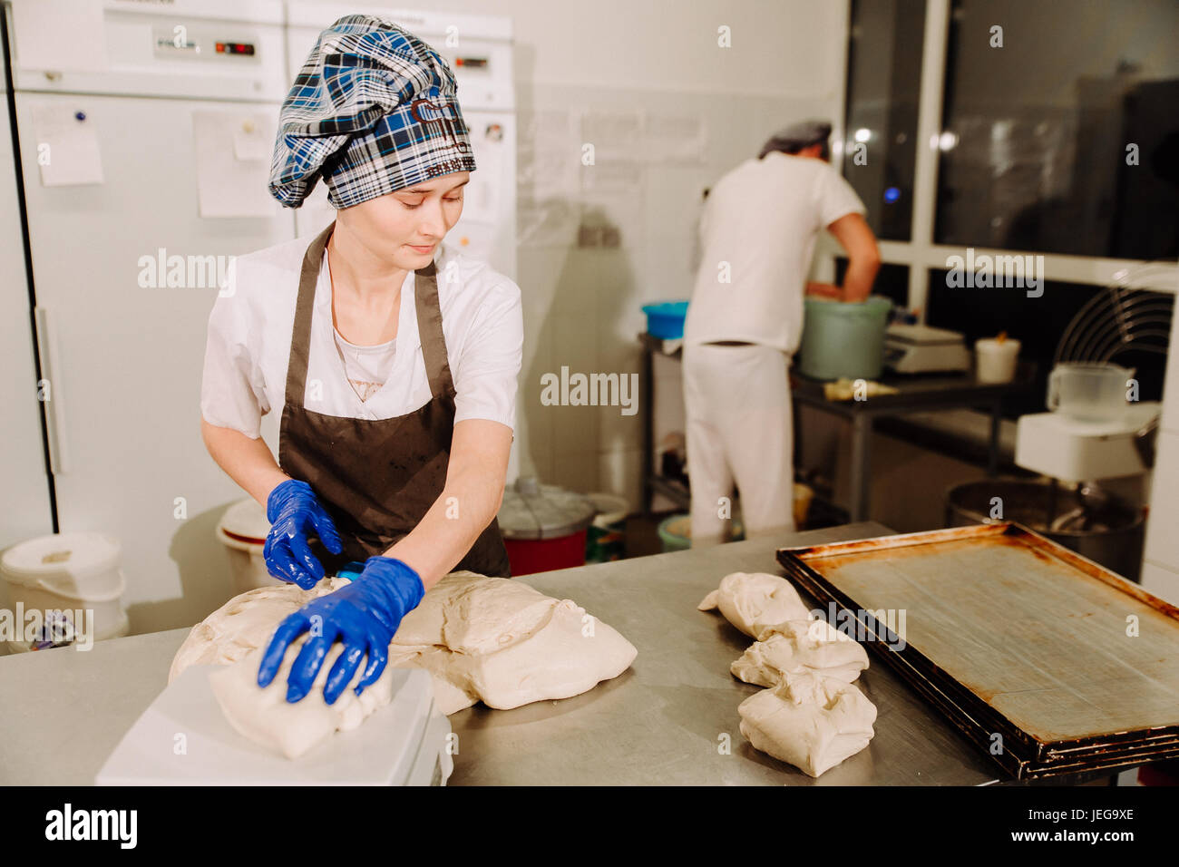 Femmina mani baker taglio pezzo di pasta con il vecchio impasto coltello raschiatore su panetteria di metallo la superficie del tavolo Foto Stock