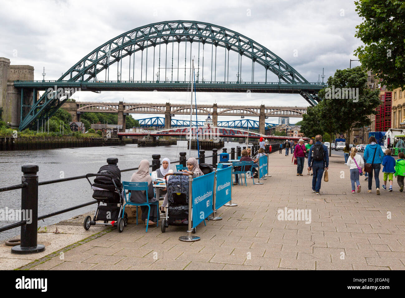 Newcastle-upon-Tyne, Inghilterra, Regno Unito. Il Quayside Scene di strada. Le donne musulmane aventi i rinfreschi. Tyne Bridge, ponte girevole, altri ponti in background. Foto Stock
