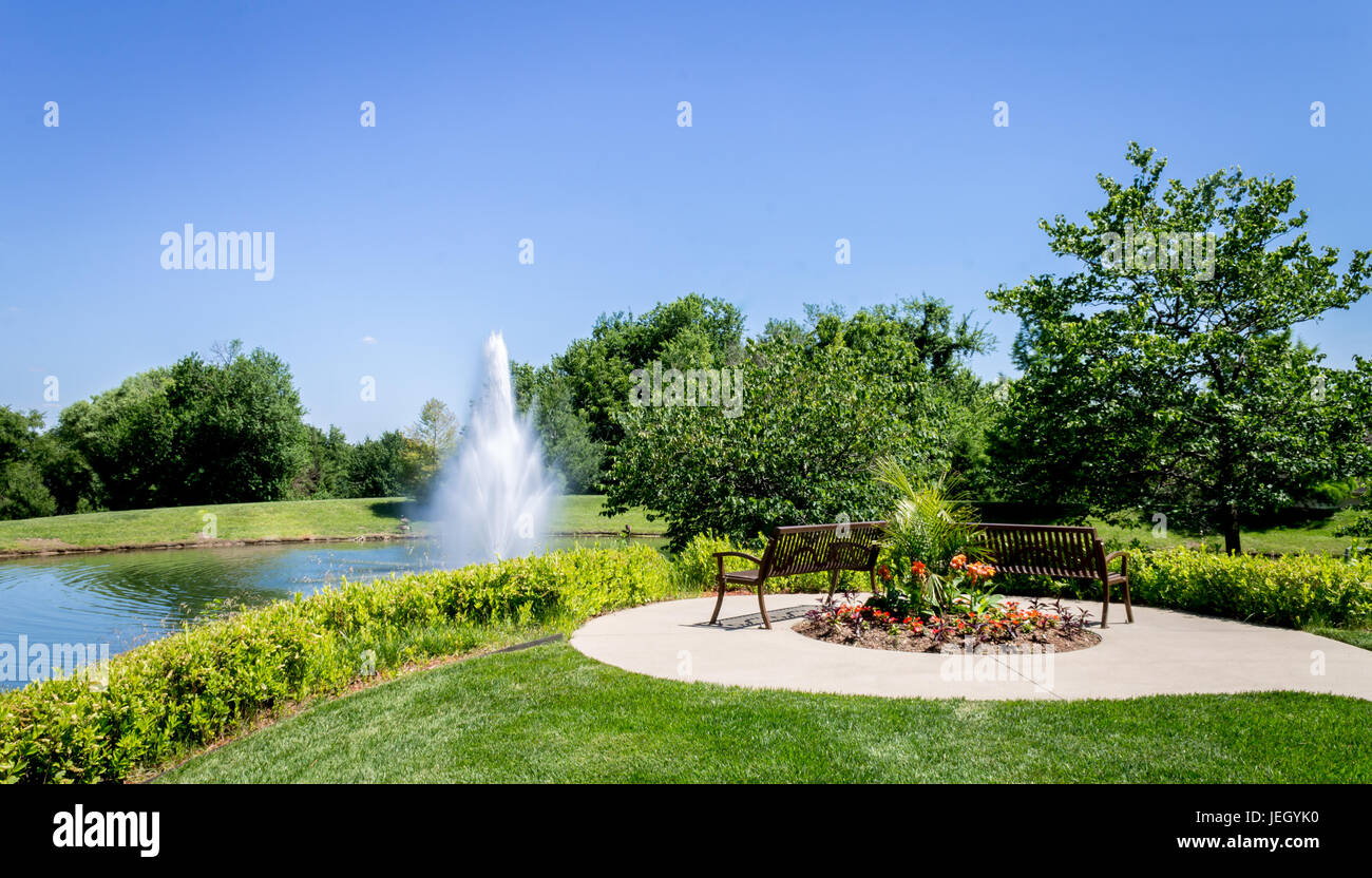 Tranquilla area di sosta davanti a un laghetto con una grande fontana Foto Stock
