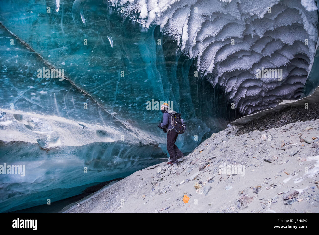 Un uomo esplora un tunnel sotto il ghiaccio del ghiacciaio Canwell in Alaska Range in inverno; Alaska, Stati Uniti d'America Foto Stock