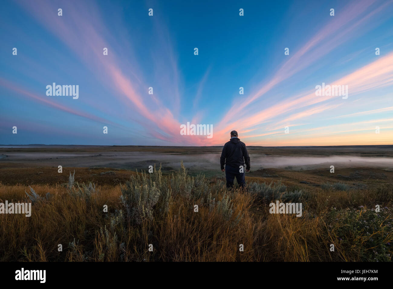 Un uomo sta guardando guardando il sunrise colore sopra il francese sulla Valle del fiume nelle praterie del Parco Nazionale; Saskatchewan, Canada Foto Stock