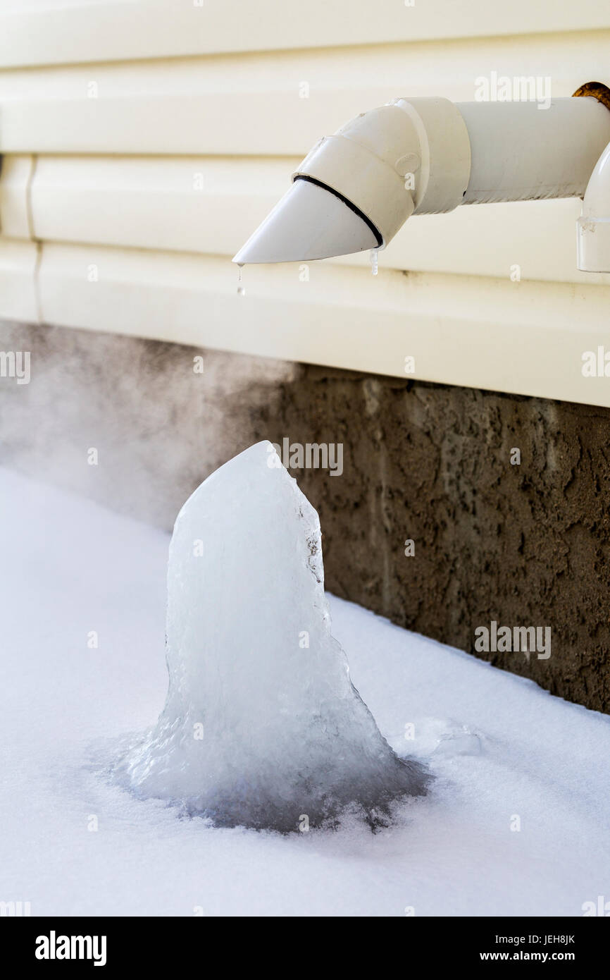 Close-up del forno della tubazione di scarico sulla parte esterna della casa con blocco di ghiaccio formando; Calgary, Alberta, Canada Foto Stock