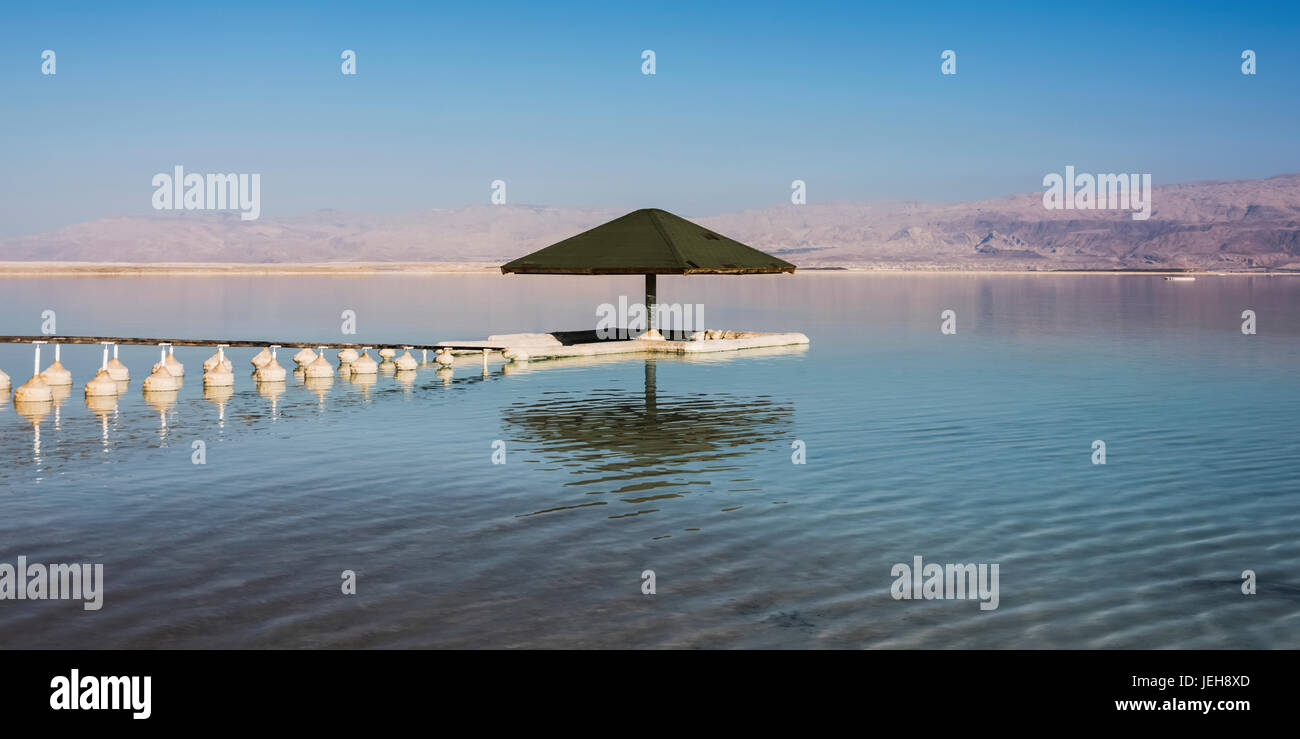 Un ombrello, boe e un dock nel Mar Morto; Distretto Sud, Israele Foto Stock
