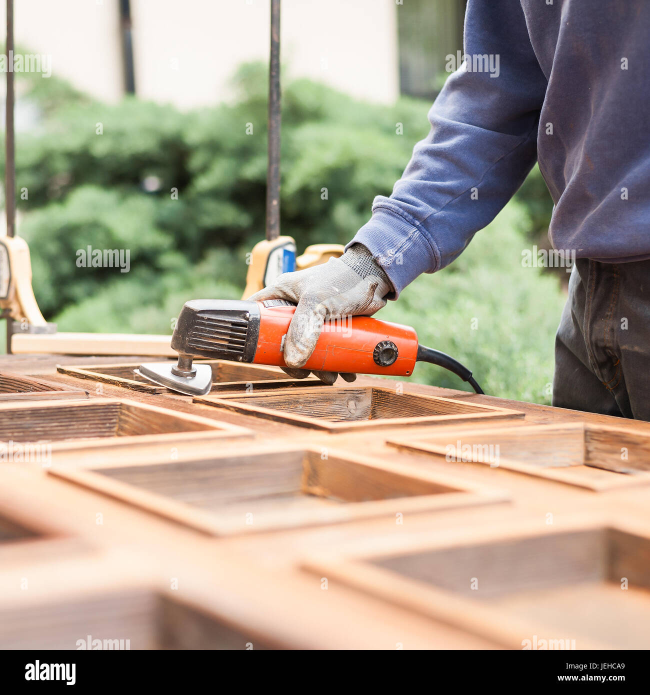 Carpenter al lavoro con la smerigliatrice angolare. La manutenzione e il restauro di una vecchia porta di legno. Foto Stock