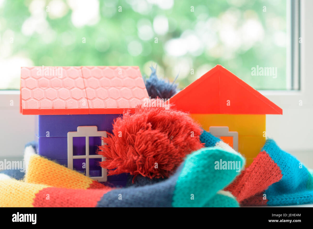 Casa giocattolo sul davanzale della finestra avvolto in una sciarpa. Il riscaldamento della casa. Foto Stock