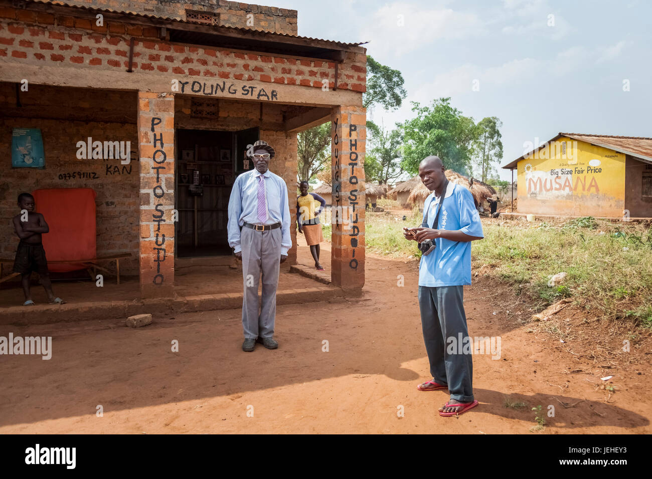 Un fotografo con fotocamera stand al di fuori di una foto studio edificio: Uganda Foto Stock