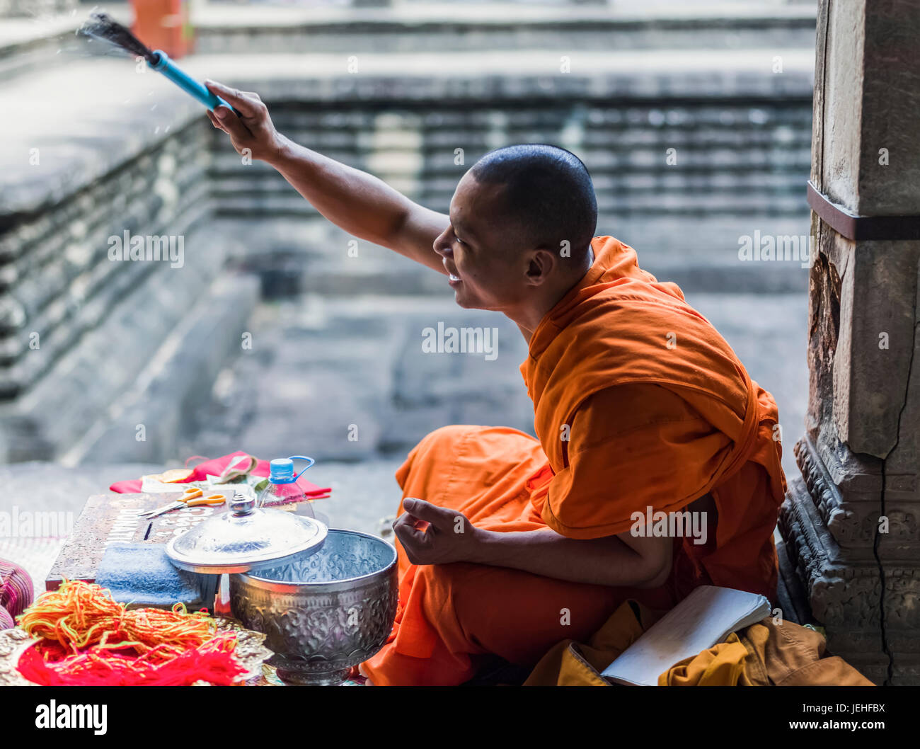 Un monaco si siede a Angkor Wat; Krong Siem Reap, Siem Reap Provincia, Cambogia Foto Stock