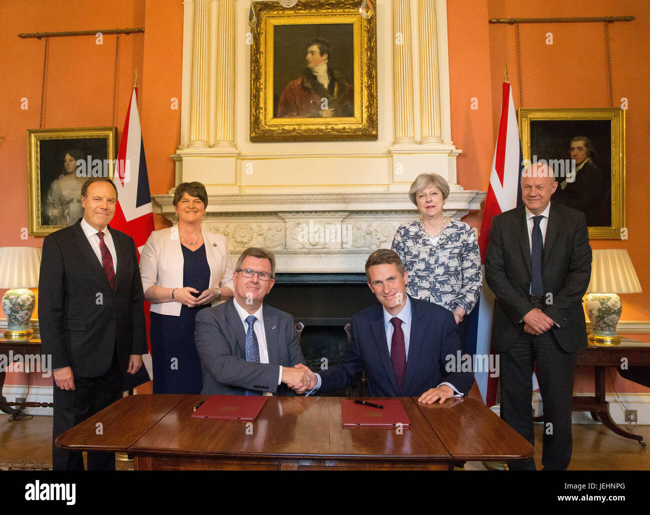 Il primo ministro Theresa Maggio stand con il primo segretario di Stato di Damian verde (a destra), DUP leader Arlene Foster (seconda a sinistra), DUP vice leader Nigel Dodds (sinistra), come DUP MP Sir Jeffrey Donaldson (terza a destra) stringe la mano con il Segretario Parlamentare al tesoro, e Chief Whip, Gavin Williamson, all'interno di 10 Downing Street, Londra, dopo la partizione DUP hanno convenuto un accordo per il supporto di una minoranza governo conservatore. Foto Stock