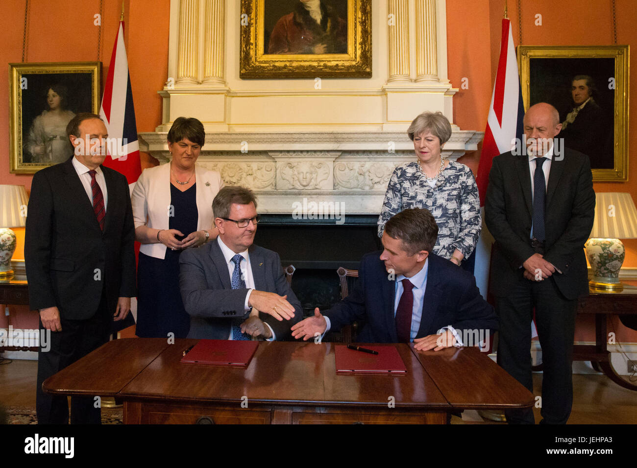 Il primo ministro Theresa Maggio stand con il primo segretario di Stato di Damian verde (a destra), DUP leader Arlene Foster (seconda a sinistra), DUP vice leader Nigel Dodds (sinistra), come DUP MP Sir Jeffrey Donaldson (terza a destra) stringe la mano con il Segretario Parlamentare al tesoro, e Chief Whip, Gavin Williamson, all'interno di 10 Downing Street, Londra, dopo la partizione DUP hanno convenuto un accordo per il supporto di una minoranza governo conservatore. Foto Stock