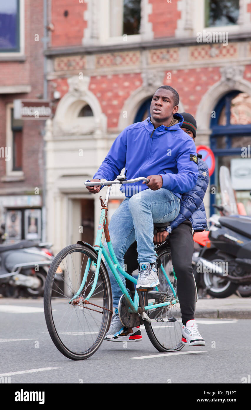 AMSTERDAM-26 AGOSTO 2014. Ragazzo del Suriname su una bicicletta blu arrugginita. Secondo il comune, 177 diverse nazionalità residenti ad Amsterdam. Foto Stock