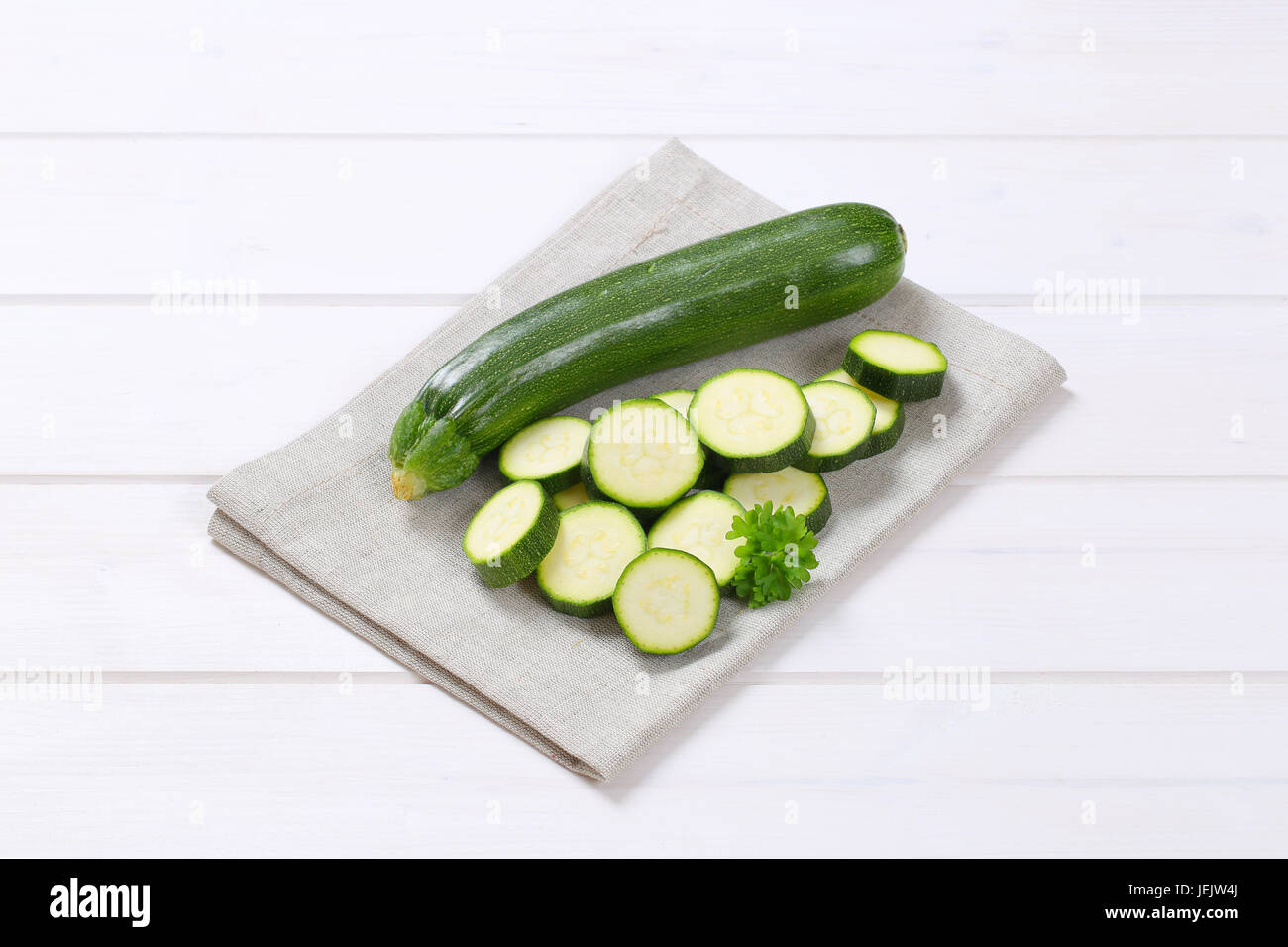 Intero e fette di zucchine verde sul posto beige mat Foto Stock