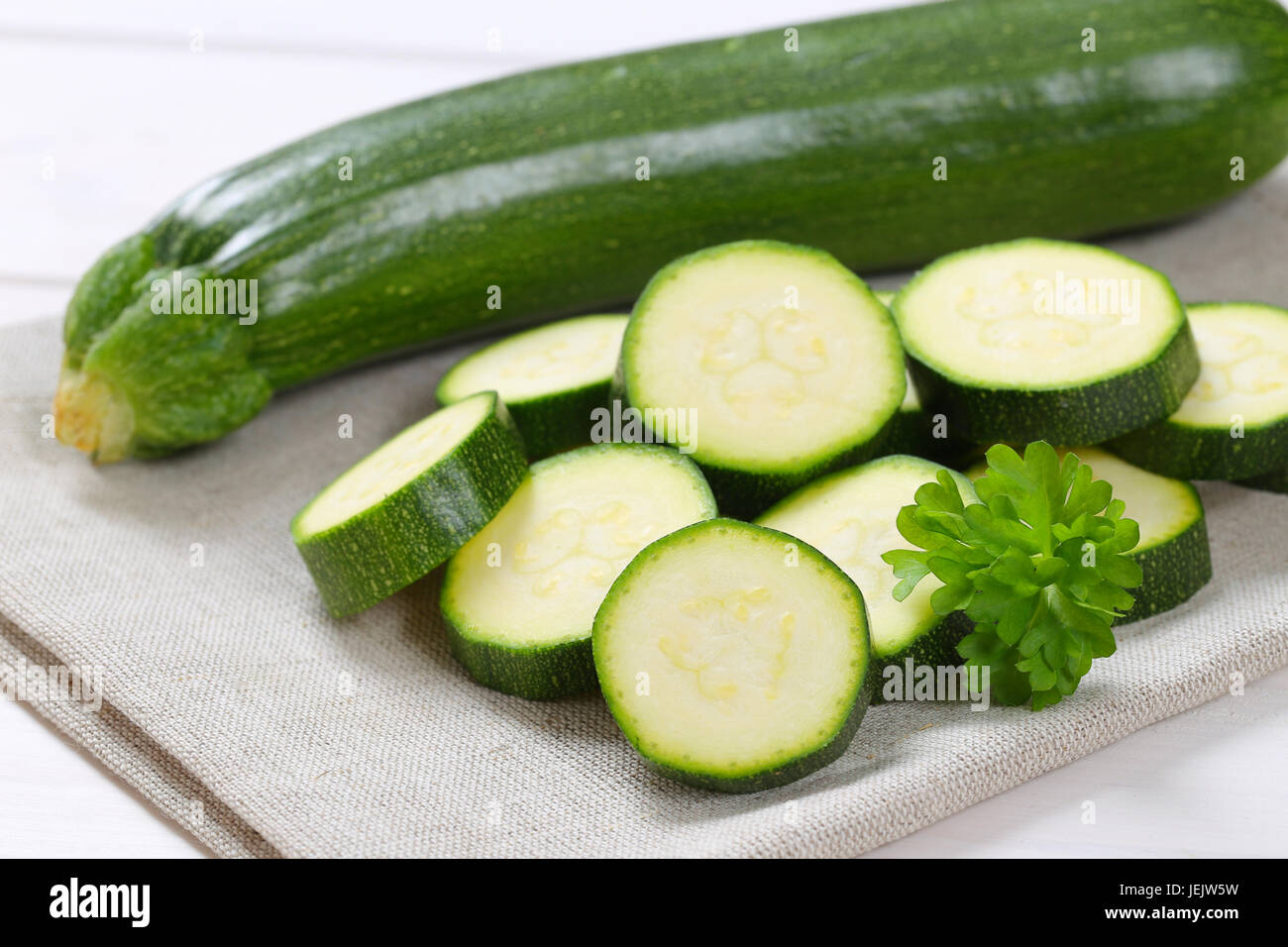Intero e fette di zucchine verde sul posto beige mat - close up Foto Stock