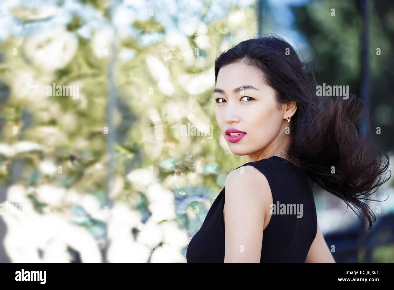 Asian giovane donna contro la parete a specchio esterno Foto Stock