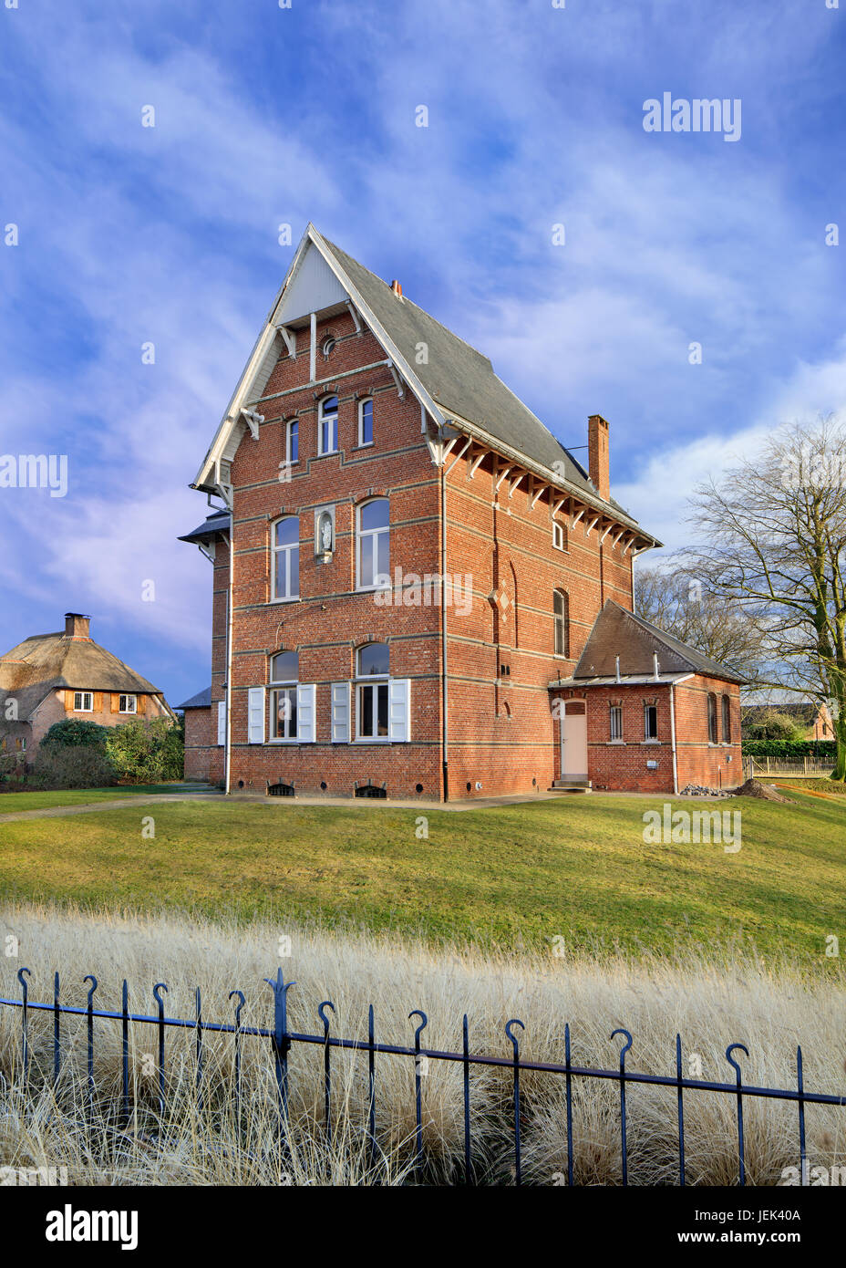 Imponente antica canonica contro nuvoloso cielo blu, Ravels, Fiandre, in Belgio Foto Stock