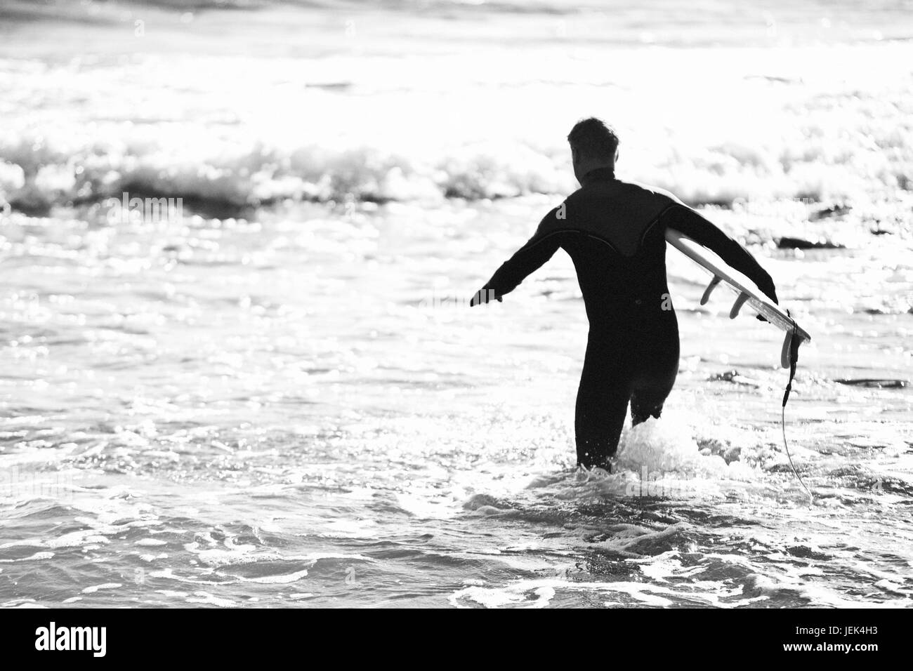 Silhouette di surfer in esecuzione in mare Foto Stock