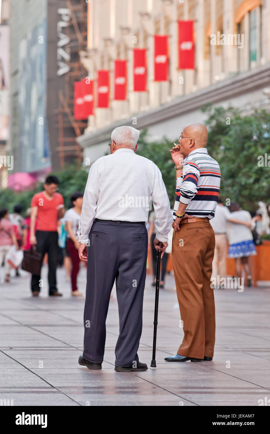 Uomo vecchio con un bastone in una strada dello shopping. La popolazione di anziani (60 o più vecchio) in Cina è di circa 128 milioni, uno in ogni dieci persone. Foto Stock