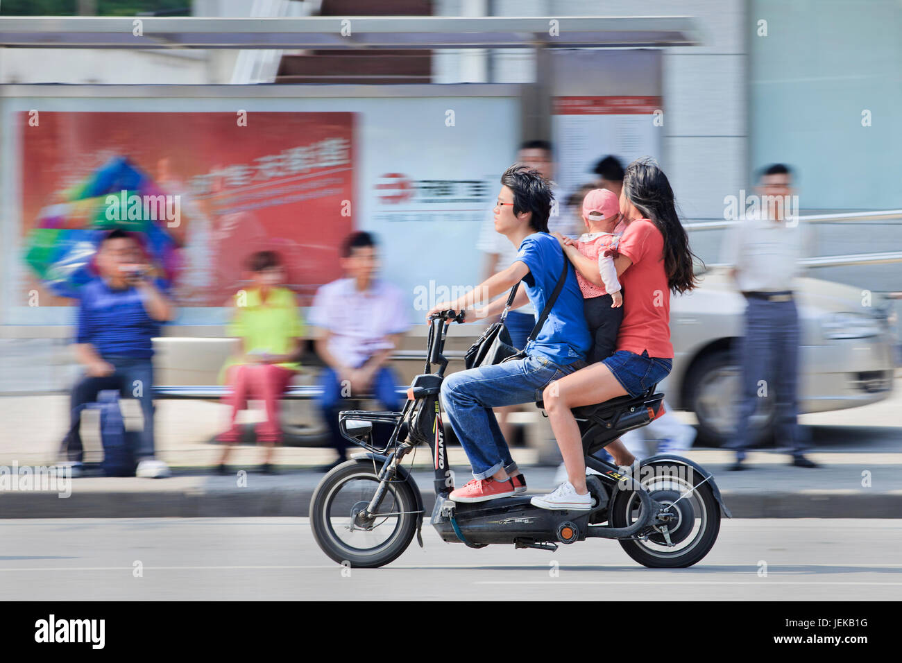 Coppia con bambini sulla bicicletta elettrica. Il governo cinese politica di pianificazione familiare limita ufficialmente sposato, urbana coppie o aventi un solo bambino. Foto Stock