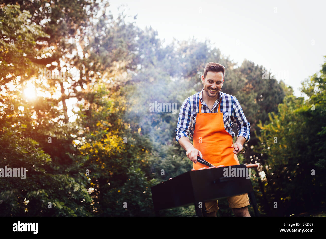 Bel giovane prepara barbecue esterno per gli amici Foto Stock