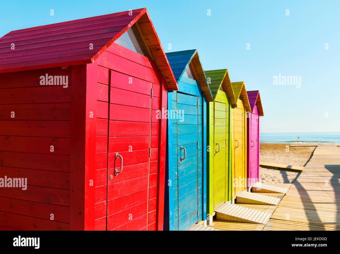 Primo piano di alcuni pittoresca spiaggia di capanne di colori diversi in una spiaggia solitaria, con l'oceano sullo sfondo Foto Stock