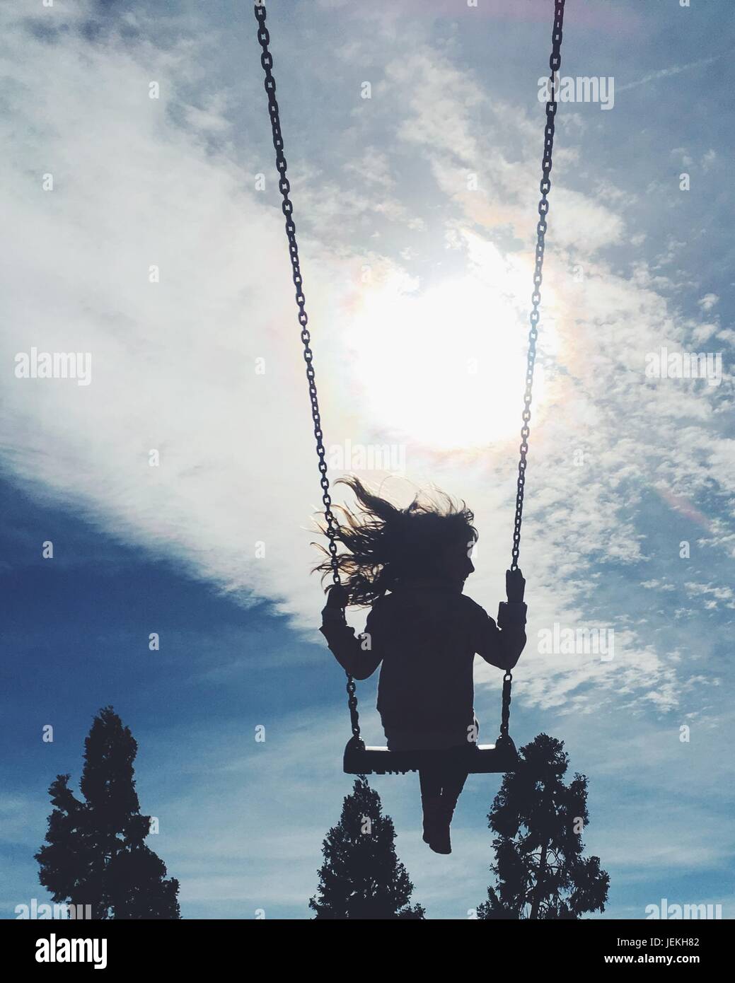 Silhouette di una ragazza basculante in una swing corda Foto Stock