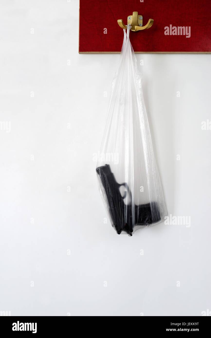 Una pistola in un sacchetto di plastica appeso ad un gancio Foto Stock