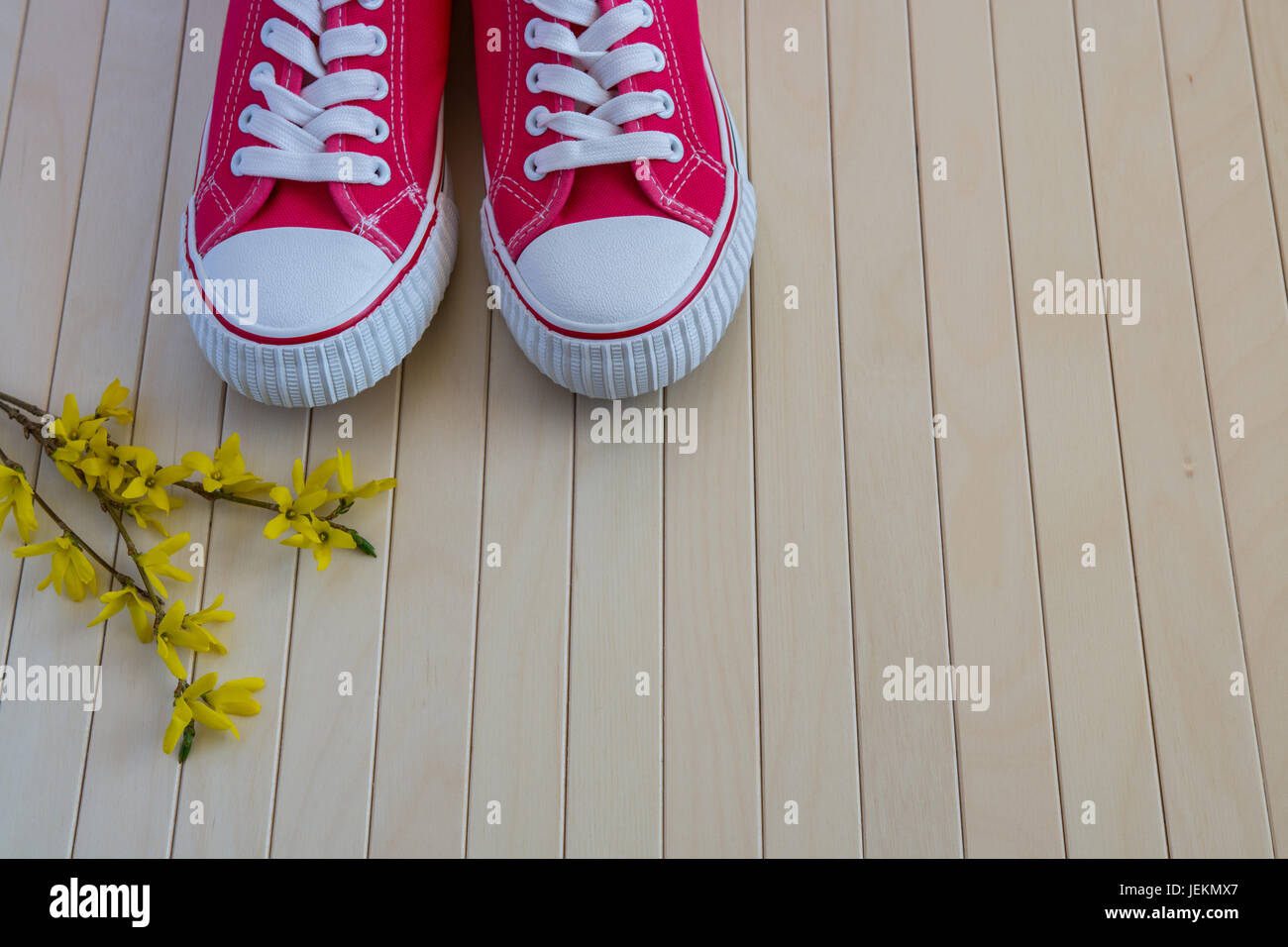 Coppia di sneakers con fiori di colore giallo su sfondo di legno Foto Stock