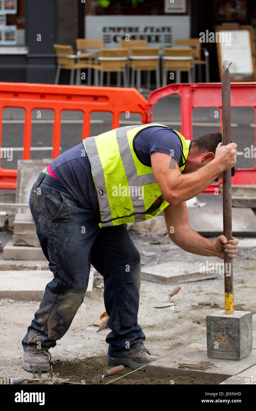 Un operaio dall'ingegneria civile società "Land & Servizi di costruzione" la posa di pavimentazione in calcestruzzo lastre lungo la zona Nethergate a Dundee, Regno Unito Foto Stock