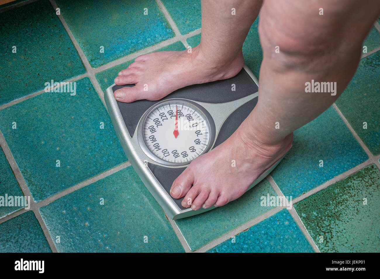 Un molto sovrappeso persona stessa di pesatura o di se stesso su una bilancia da bagno Foto Stock