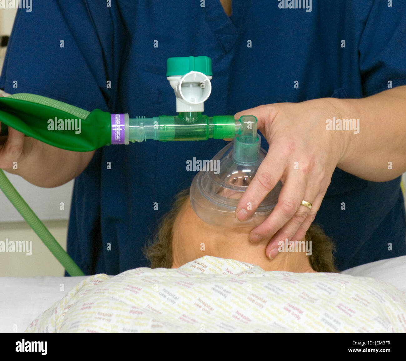 Recupero di ODP praticante sovrintende al paziente di svegliarvi dall'anestesia, utilizzando un sacco di maschera di valvola per fornire la ventilazione a pressione positiva. Foto Stock