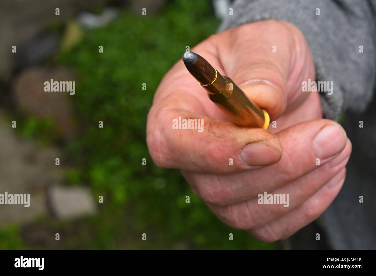 Old man mano che tiene e mostra uno 7,62 mm munizioni calibro bullet Foto Stock