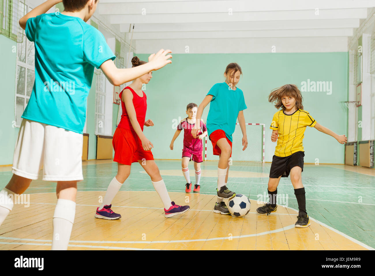 I bambini che giocano a calcio nella scuola di sport hall Foto Stock
