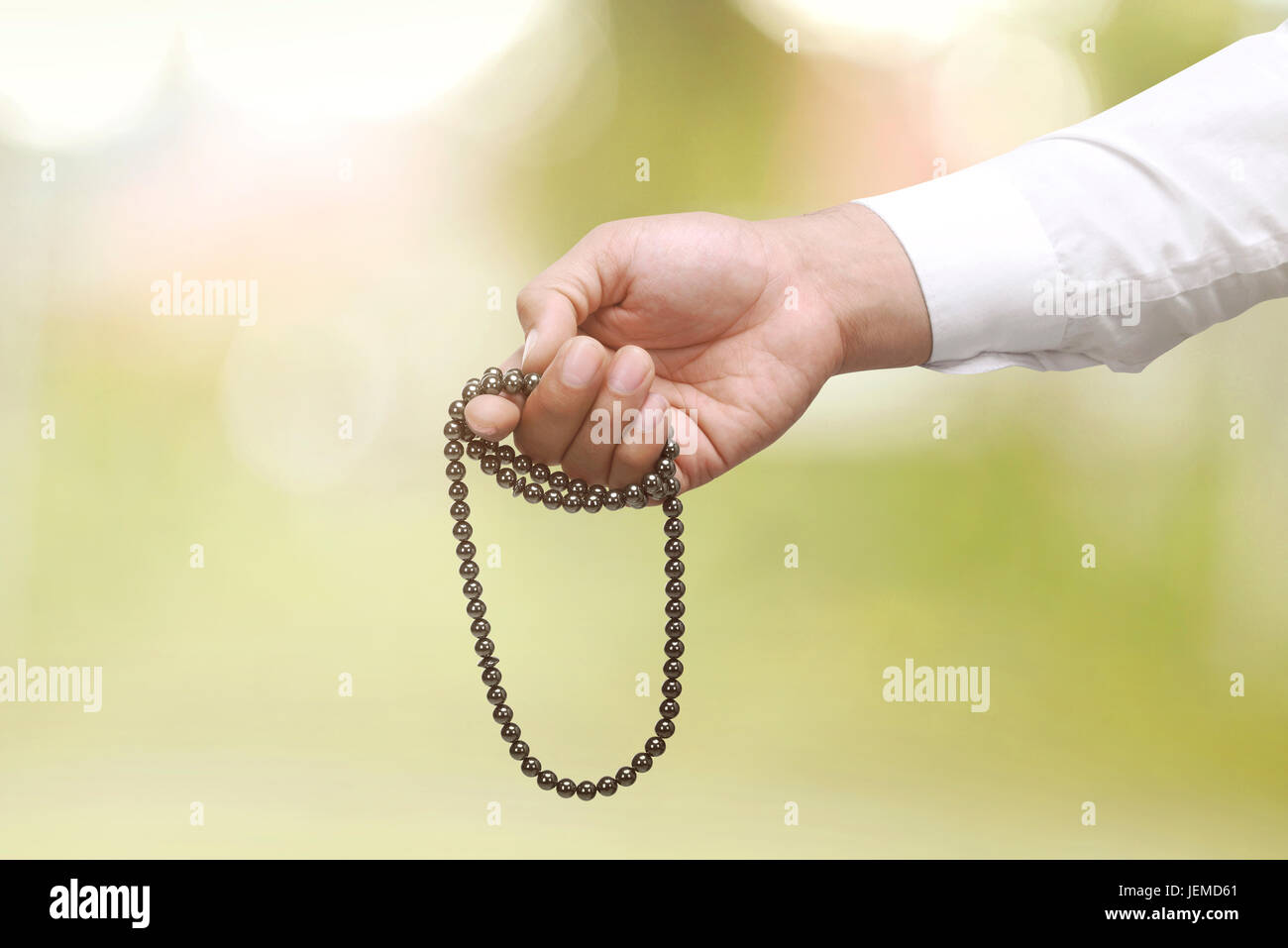 Uomo musulmano di pregare con i grani di preghiera su blur sullo sfondo Foto Stock