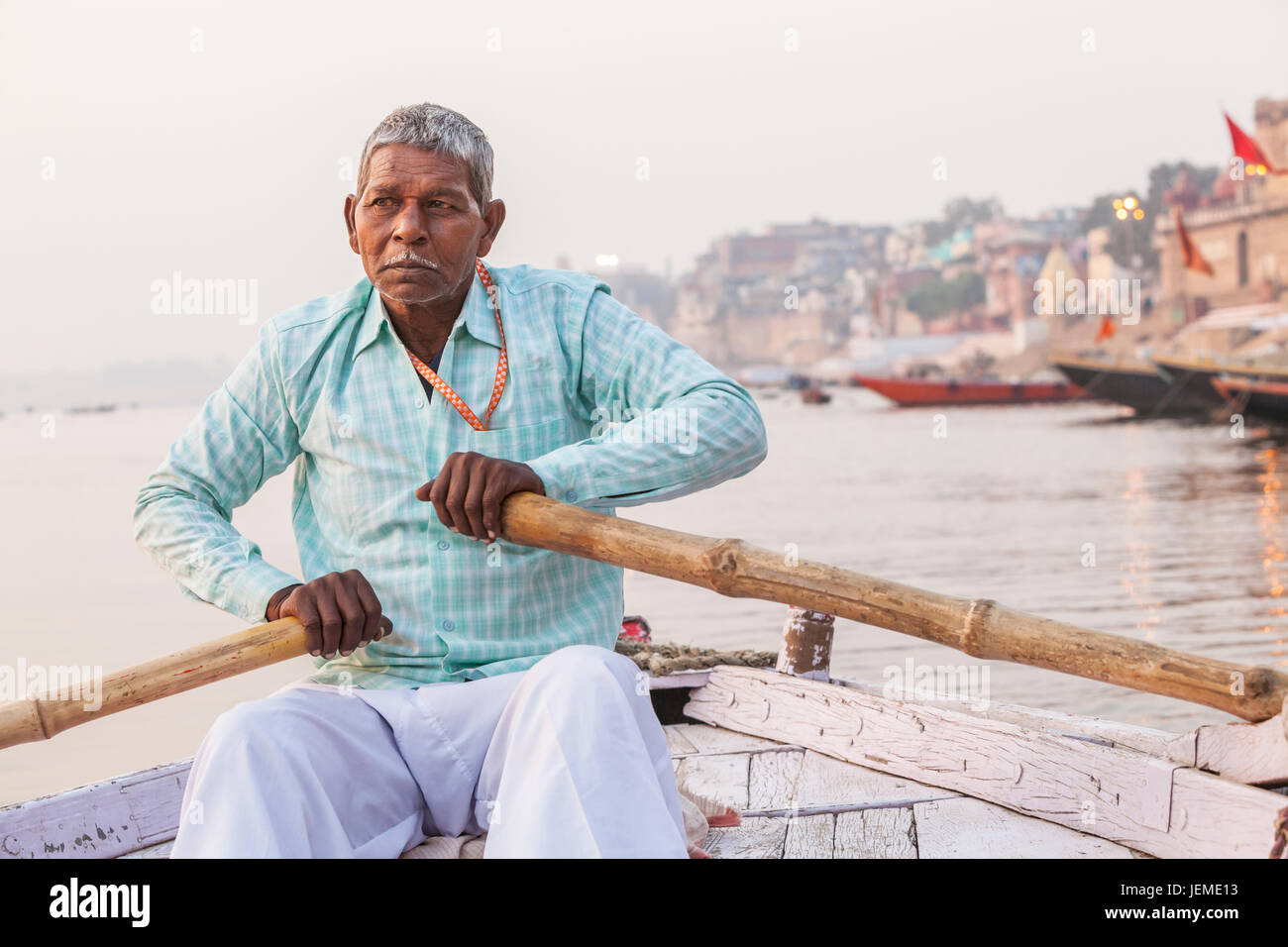 Un uomo indiano remare una barca per escursioni sul fiume Gange, Varanasi (India). Foto Stock