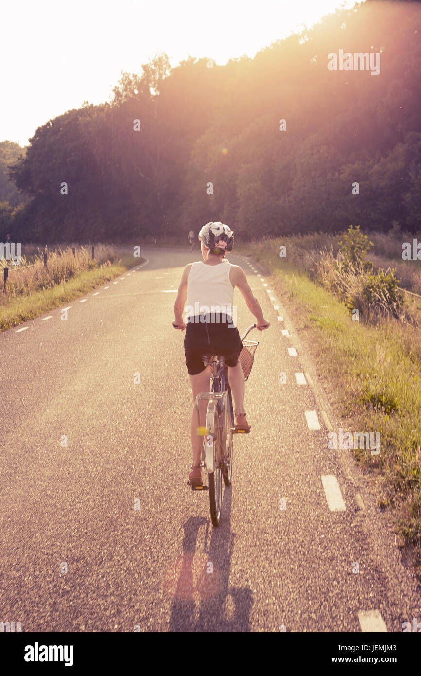Donna in bicicletta attraverso strade di campagna Foto Stock