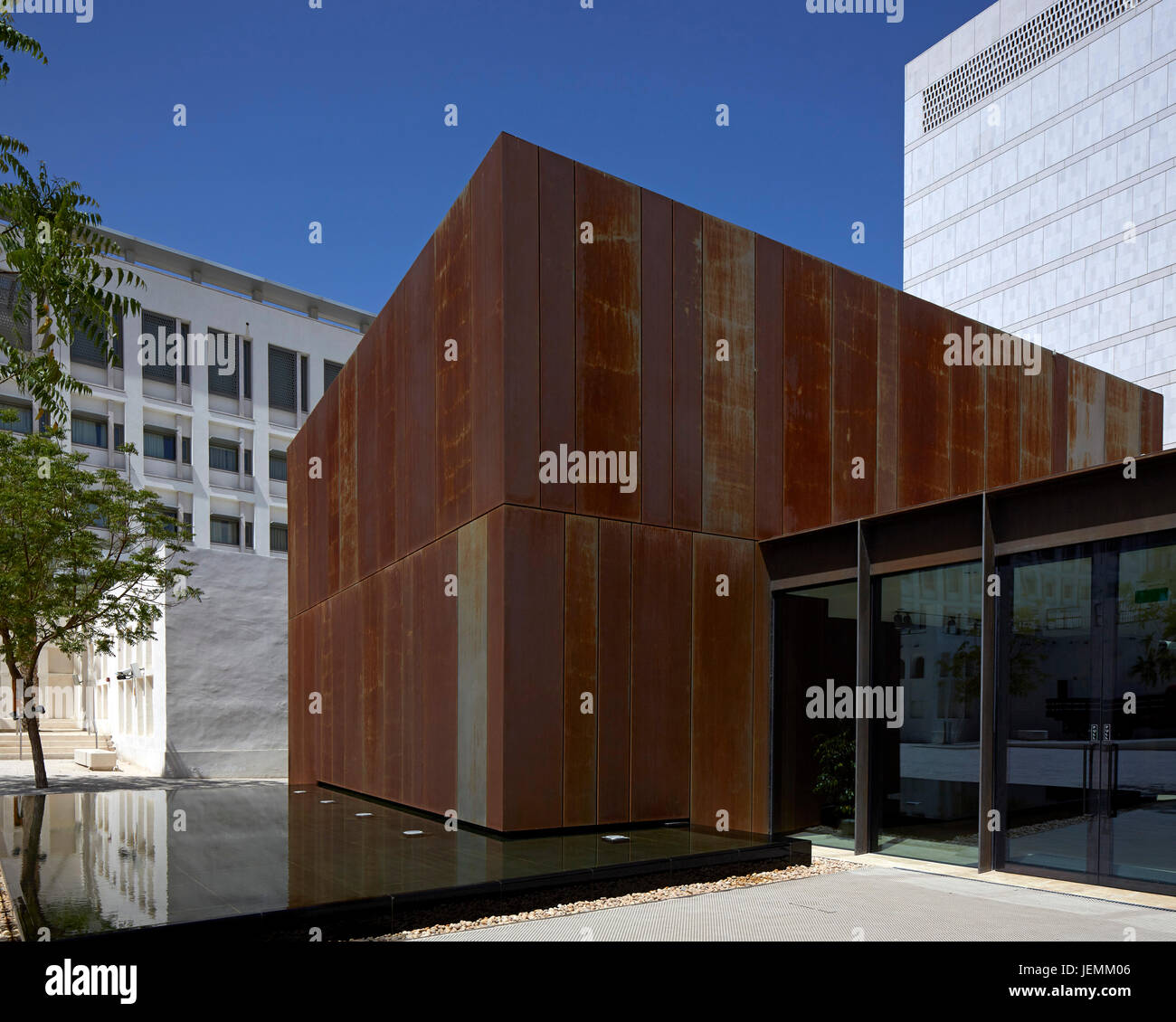 Vista laterale che mostra in acciaio Corten cubo su funzione dell'acqua. Company House, Doha, Qatar. Architetto: John McAslan e partner , 2016. Foto Stock