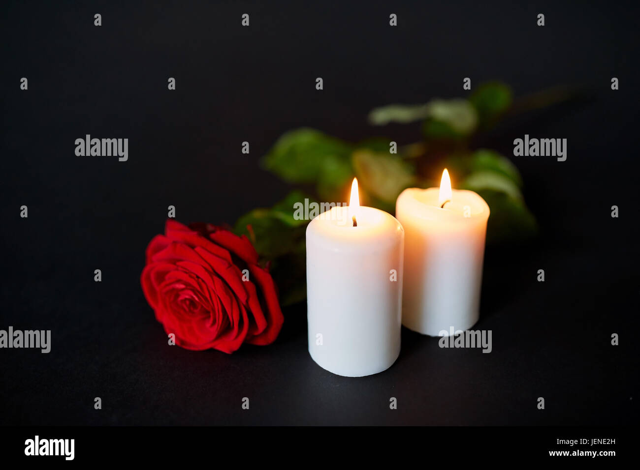 Red rose e candele accese su sfondo nero Foto Stock