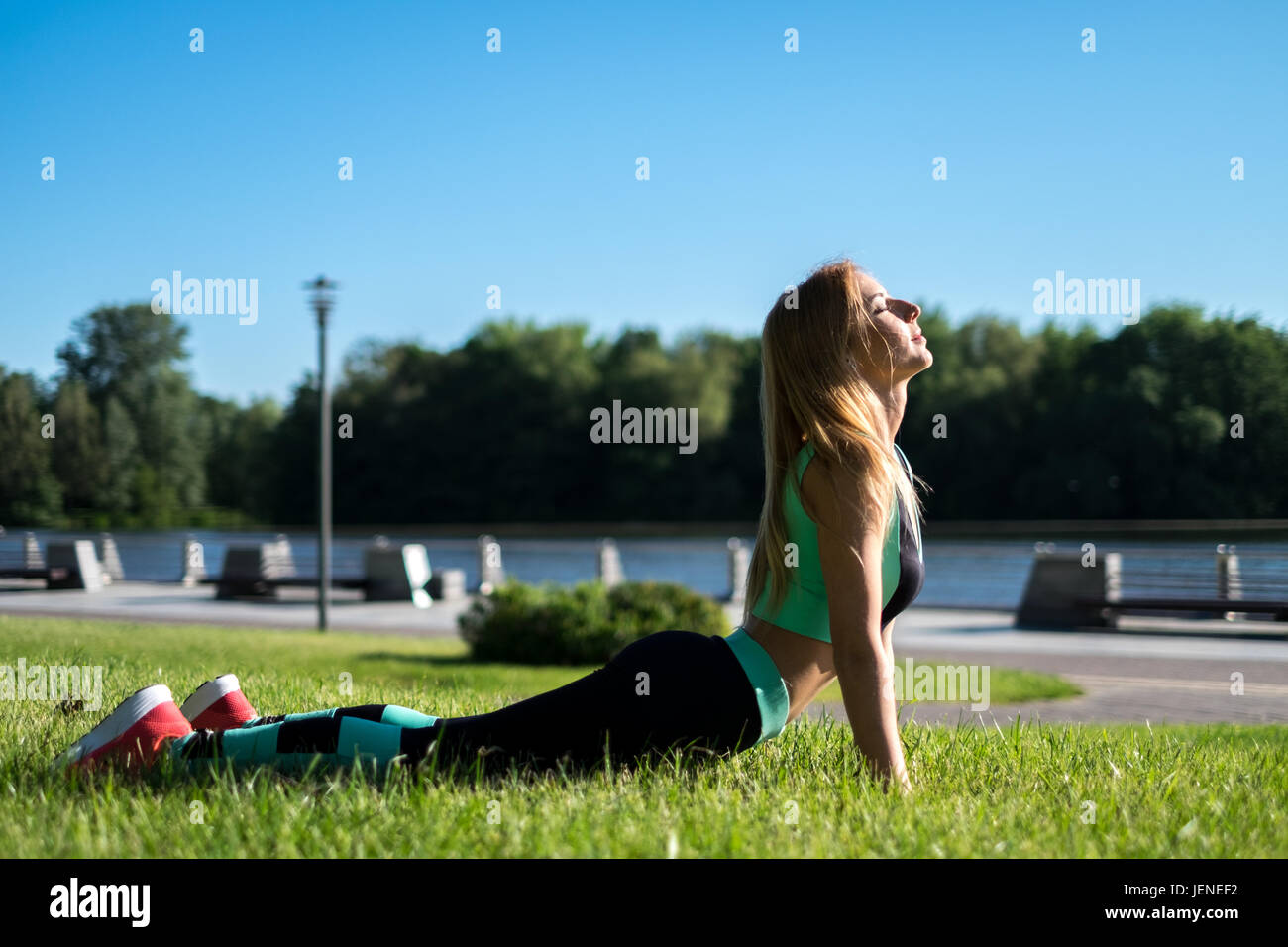 Donna sdraiata su erba facendo un yoga posa cobra Foto Stock