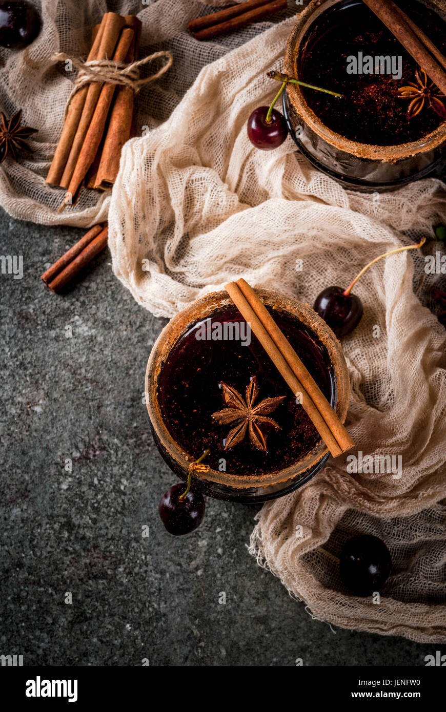 Autunno e Inverno bevande. Hot cherry sangria con cannella, anice, vino e spezie. Su di una pietra scura e lo sfondo di legno con ingredienti, copia spac Foto Stock