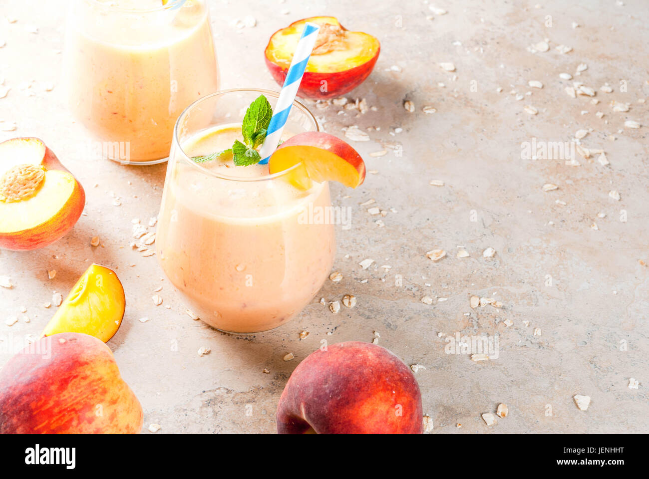 Mangiare sano. La prima colazione e snack. Bere frullati da fresco di pesche, di latte (yogurt) e farina di avena, decorato con foglie di menta, con cannucce a strisce. Su un l Foto Stock