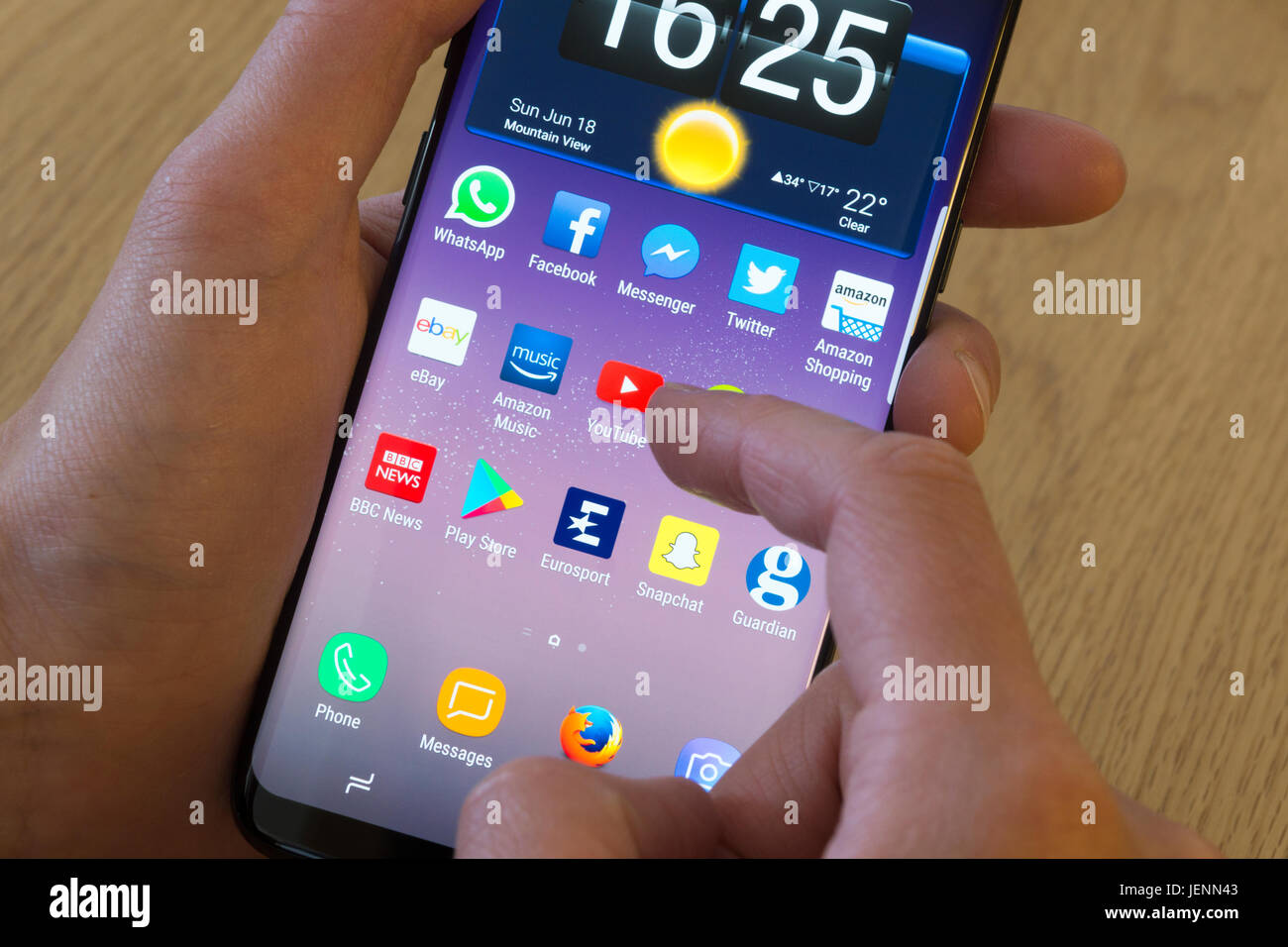 Una giovane donna selezionando l'app YouTube su uno smartphone Foto Stock